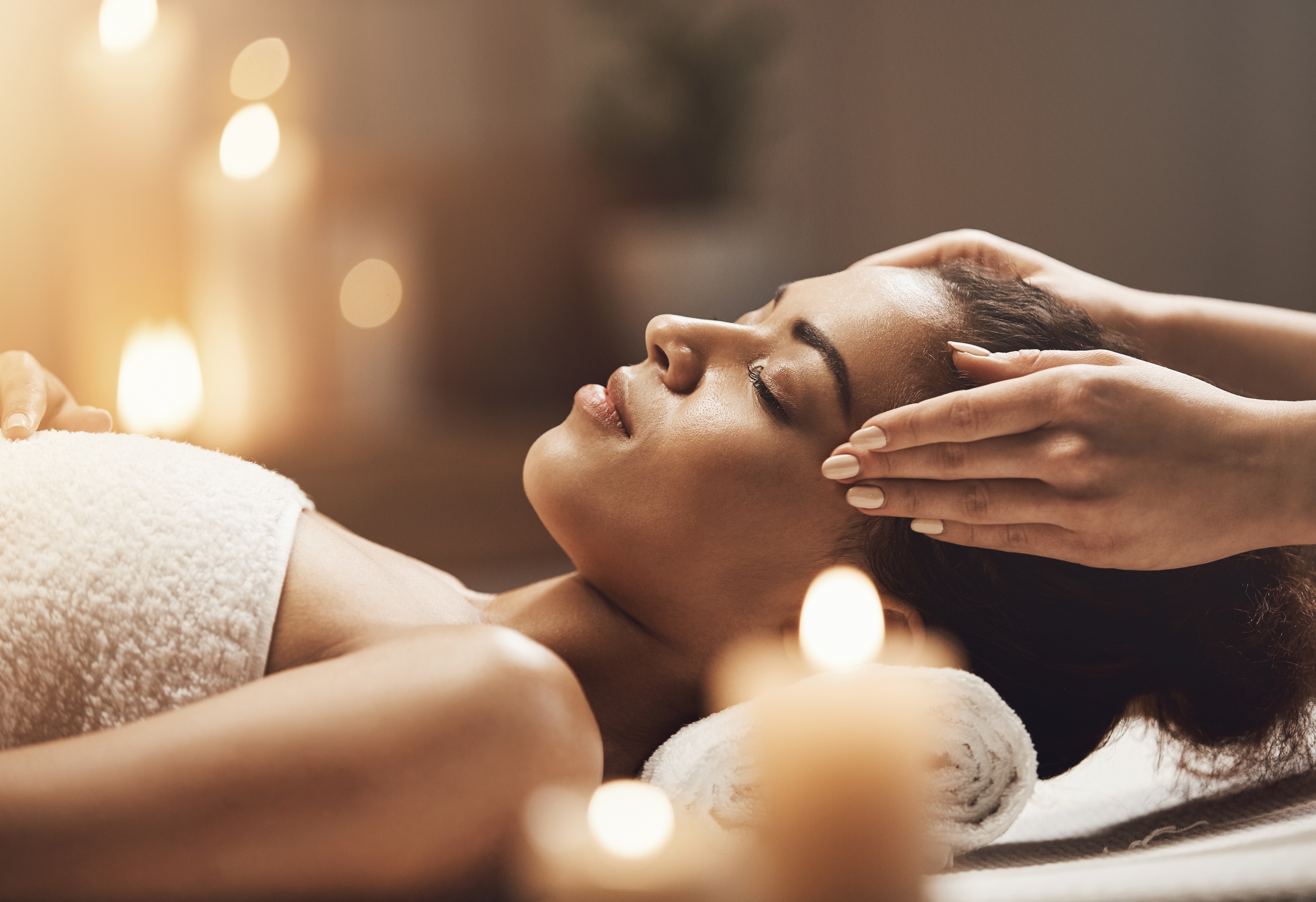 Attractive african girl enjoying face massage in spa salon. Closed eyes.